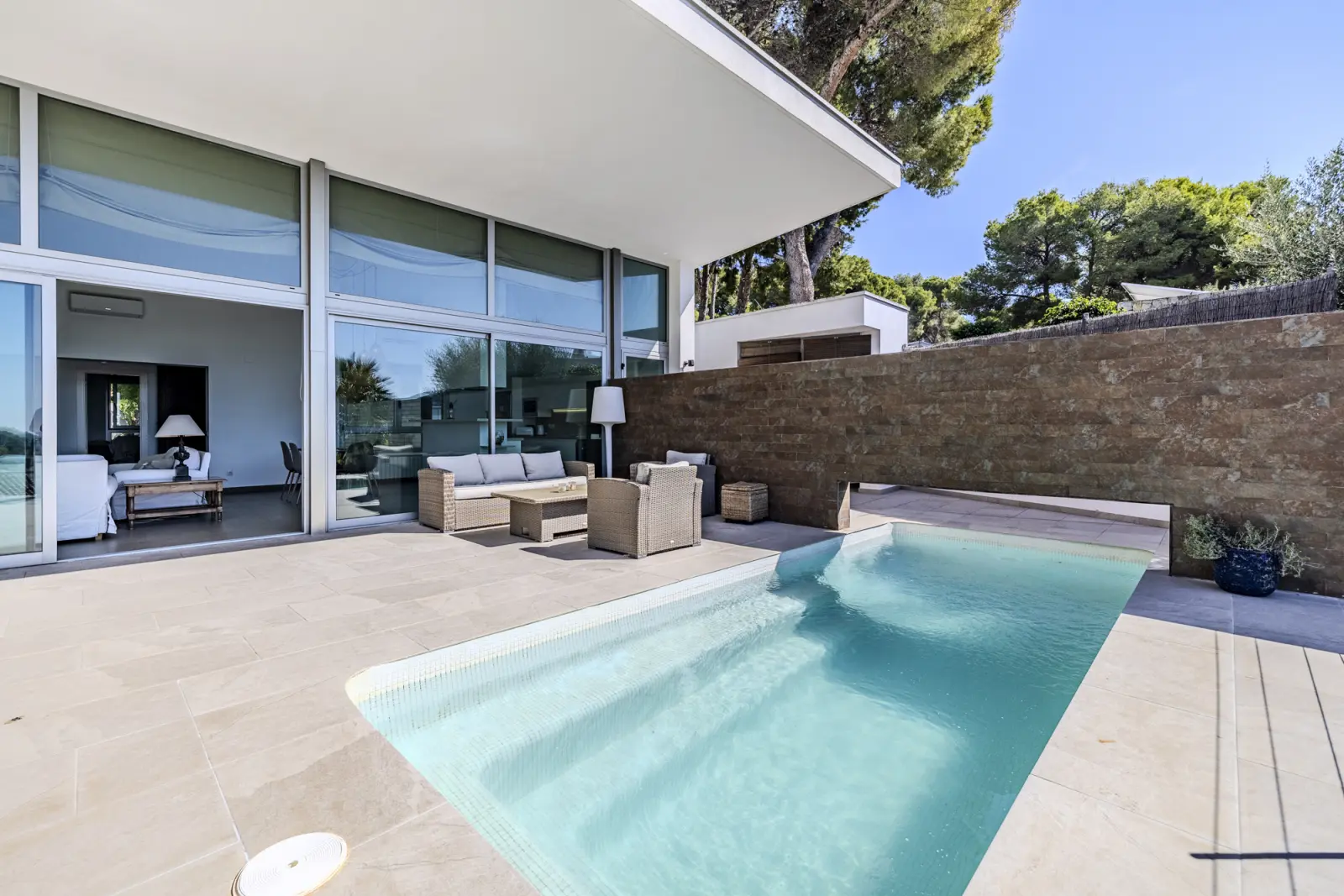 Outdoor pool beside the glazed living room and stone boundary wall