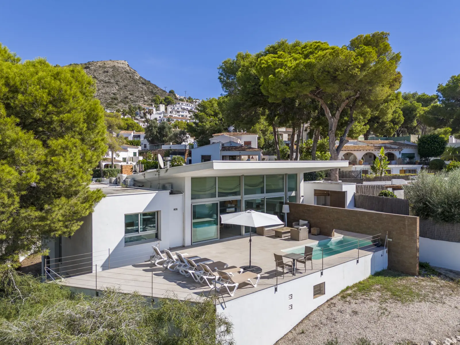 Aerial view of the villa and pool terrace beneath the wooded hillside